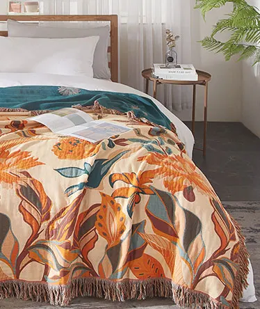 Bed with orange leaf-pattern coverlet and fringed edge