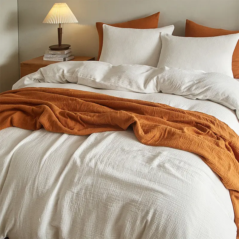 Bed with white bedding and a rust-coloured throw blanket